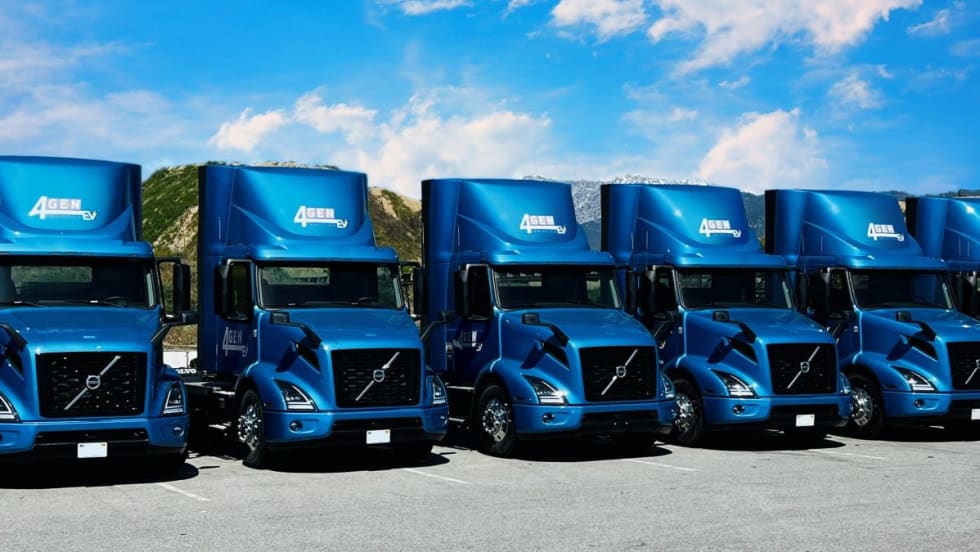 Several blue Volvo VNR Electric Trucks.