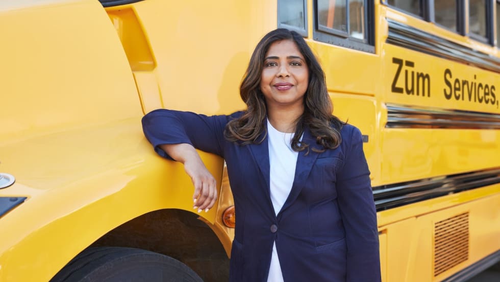 A woman stands in front of a school bus