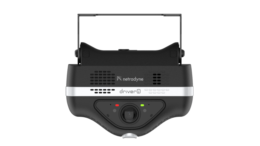 A black Netradyne driver camera with a silver band across the front, featuring a lens, two indicator lights, and ventilation grilles.