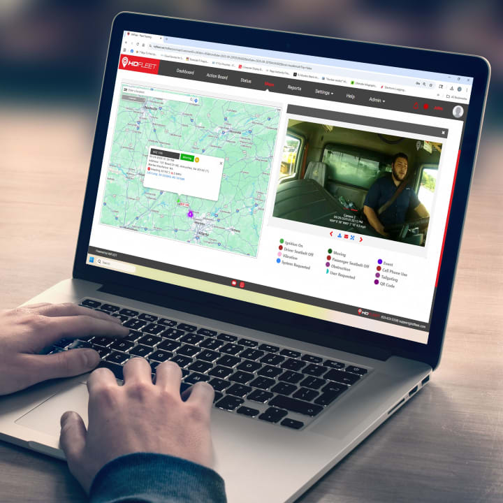 Image of a laptop wth HD Fleet web page on the screen. Web page includes image of map with navigation tracking icon on the left side and interrior video feed of the driver on right and operatoional indicators like "moving" and "seatbelt" below.
