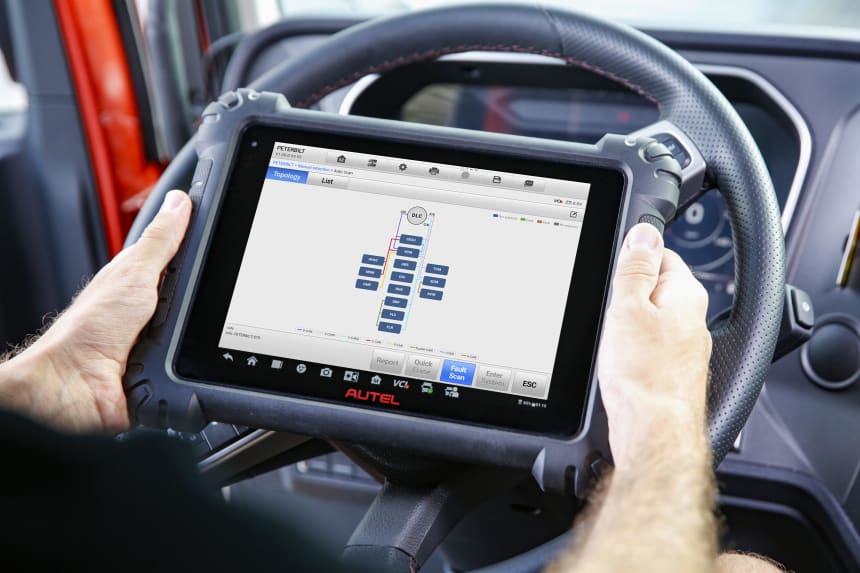 Mechanic using MS909CV car diagnostic scanner inside vehicle on a tablet with cover, displaying ECU system map on screen for fast automotive troubleshooting and repairs.