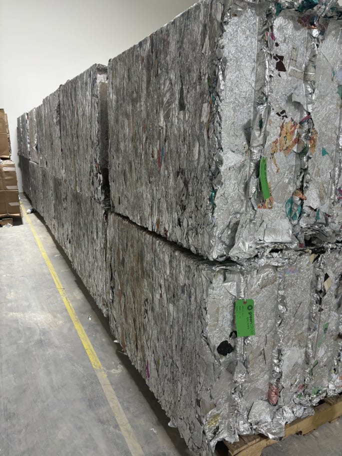 Large bales of crushed aluminum foil from hair color foils stacked on top of one another in a Green Circle facility.