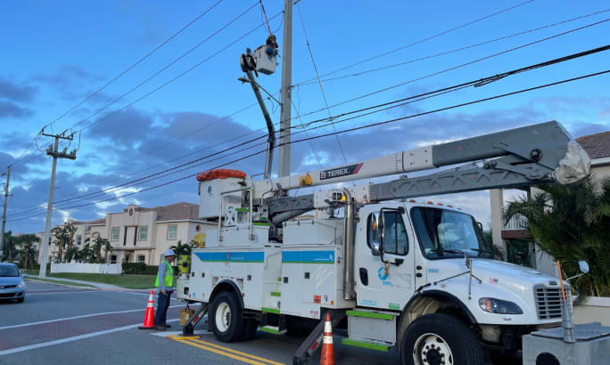 Crew repairs power lines with bucket truck.