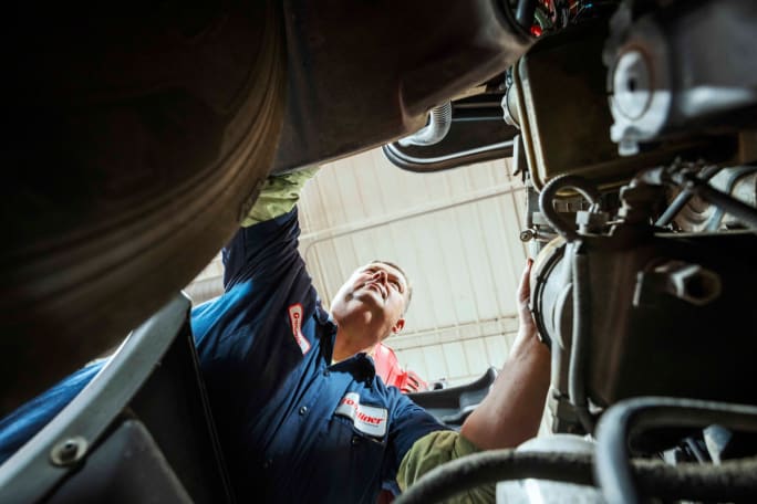 Photo shot from engine perspective looking up at a heavy duty truck technician from Foodliner