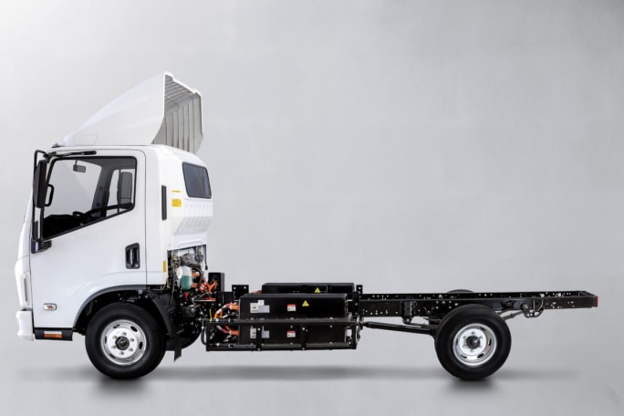 A low cab-forward white truck chassis is shown.