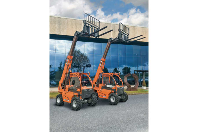 Two small rough terrain forklifts, both orange, are parked outside and office.