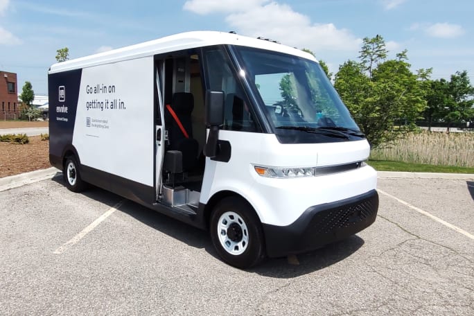 A white box truck delivery van, viewed from the front corner, passenger side, with door slid open.