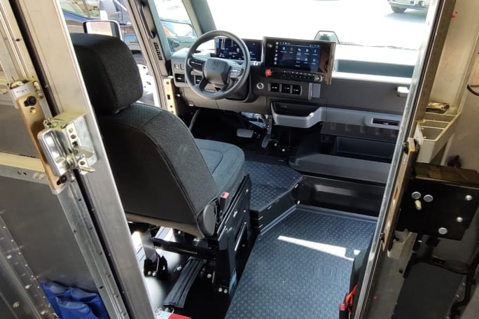 Looking through metal doors from cargo area into the driver's seat and dash.