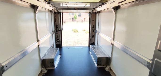 View of the interior cargo space of a white delivery van, looking toward the rear of the vehicle with the door open.