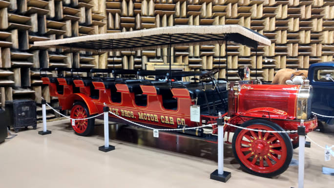 A red and black open-air bus parked in a museum..