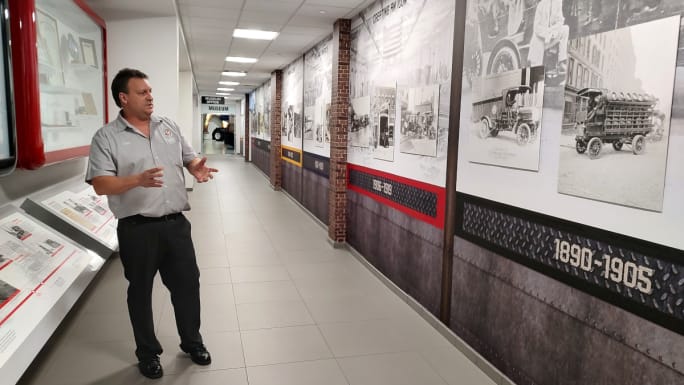 Man standing in front of vintage car images in display cases.