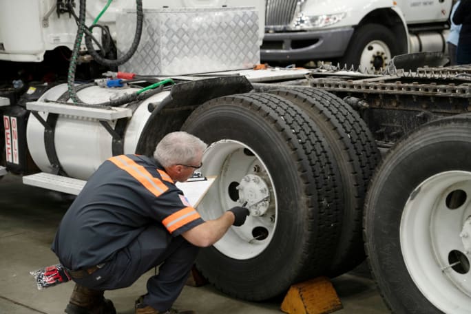 Male technician changing a tire on a truck.