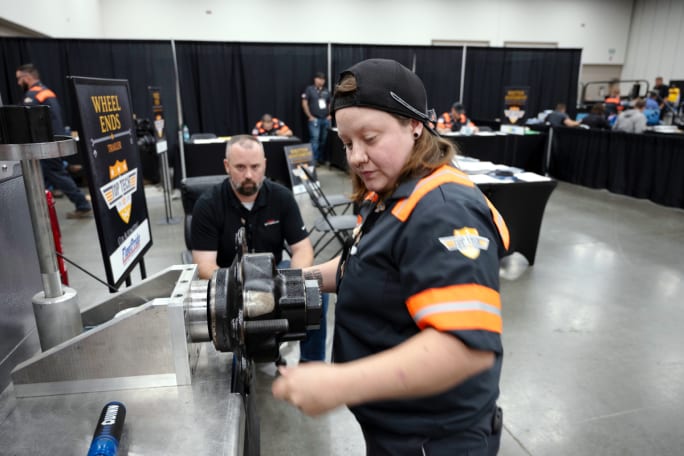 Female worker in orange and black shirt using equipment.