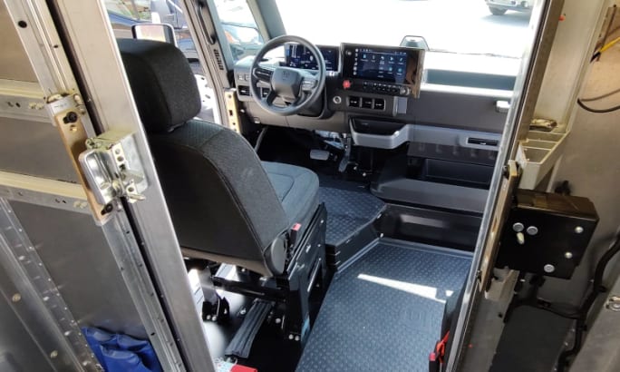 Interior view of the delivery van looking through the door from the cargo area toward the driver seat.
