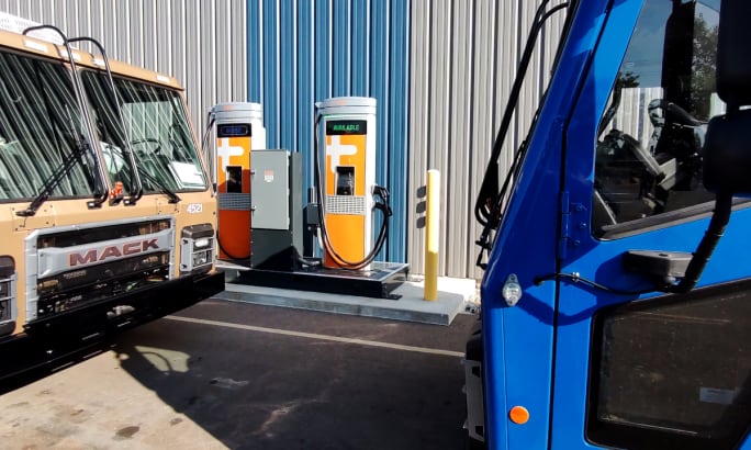 Two EV charging stations shown sitting between the cabs of two electric trucks