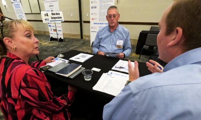 Three business people meet across a table.