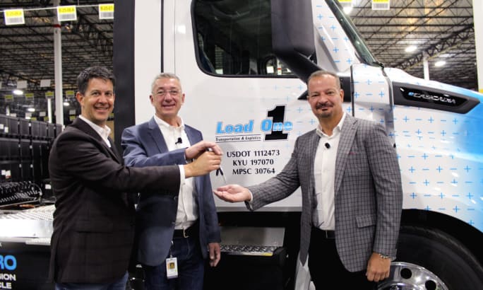 two men hand over keys to third man while standing in front of truck