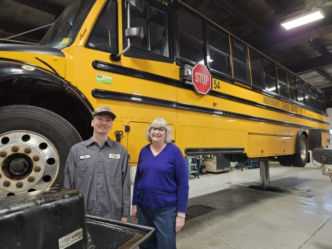 two people stand by a school bus