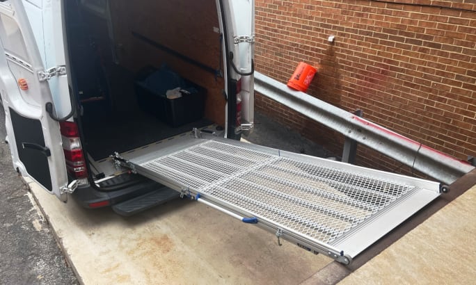 Metal loading ramp extended from cargo van to loading dock.
