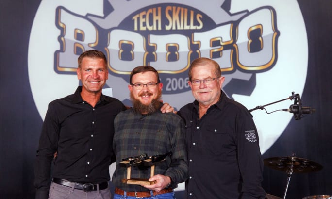 Young man receives award from two older men.