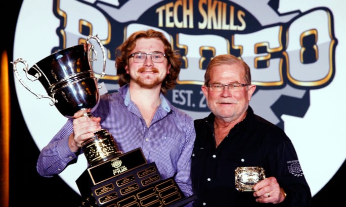 Young man receives trophy from older man.