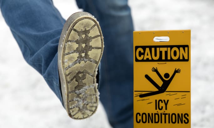 person slipping on ice with Caution: Icy conditions sign