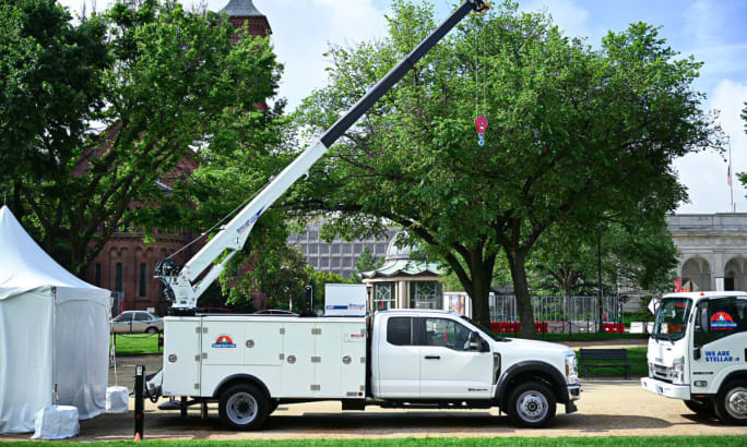 White mechanic's truck with crane extended.