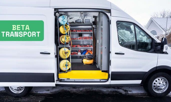 Beta Transport fleet service van with interior upfit showing secured gas cylinders, shelving, and compressor; white cargo van parked in winter suburban setting.