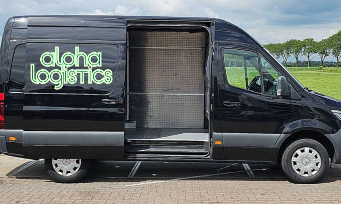 Alpha Logistics black cargo van with open sliding door, showing empty fleet upfit space with steel pegboard interior, parked in commercial lot.
