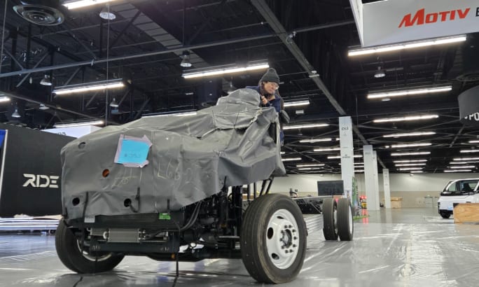 Woman parking a truck chassis in an expo booth.