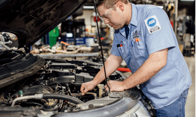 Automotive technician working under the hood of a car.