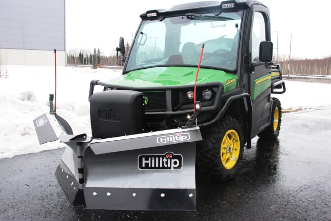 Snow plow attached to green and black UTV.