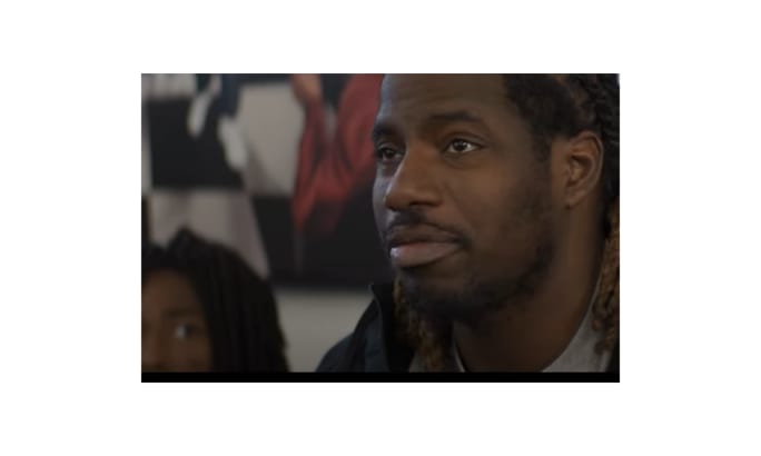 A man with braided hair looks ahead while seated indoors, featured in the ATA’s DRIVEN series highlighting the stories of professional truck drivers across the United States.