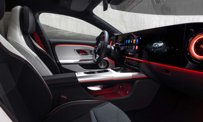 The interior of the Mercedes-Benz CLA featuring a sleek, modern design with ambient red lighting, a digital dashboard, and connected widescreen displays for infotainment and driving controls.
