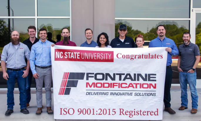 Group of individuals standing behind a Fontaine Modification banner.