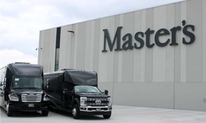 Two black shuttle vehicles parked outside a building with sign that says Master's.
