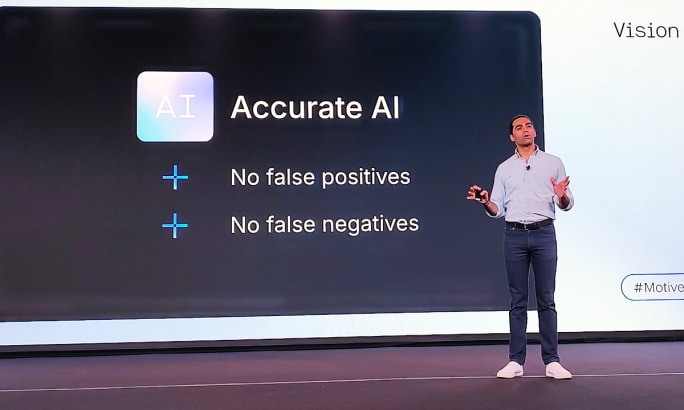 Man speaking on a stage in front of a screen that says Accurate AI.