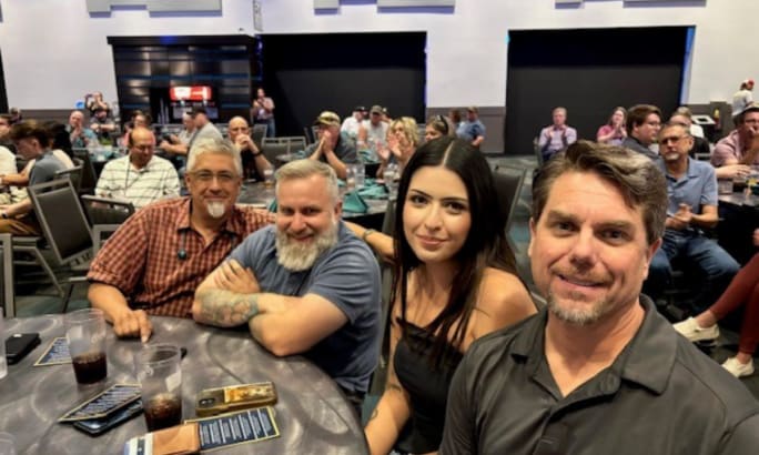Derek Canode sits with colleagues at the Idaho Student Transportation Awards Banquet, smiling at a round table with other attendees in the background.