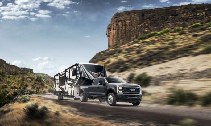 Black Ford Super Duty dually towing fifth wheel up a mountain pass.