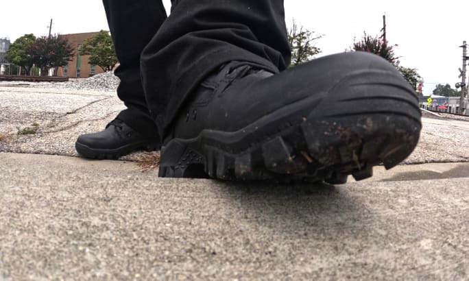 Black tactical boot on concrete ground with urban background
