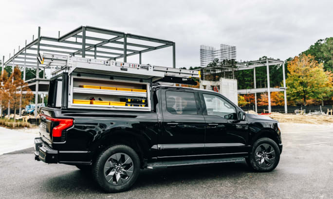 Side view of a pickup truck with a modular storage system parked at a construction site.