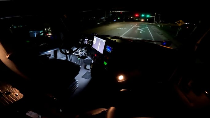 View from inside autonomous truck cab at night at stoplight