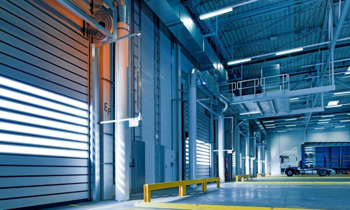 Interior of a large, modern fleet maintenance facility with truck bays and overhead lighting, illustrating the type of building that may require retrofitting.