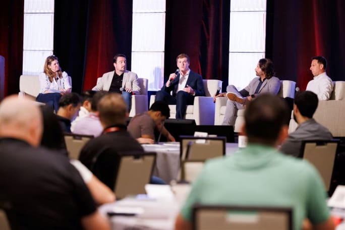 Panelists speaking at front of convention room