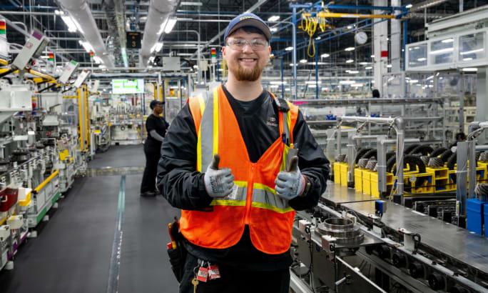 Toyota Alabama employee smiling in safety vest on differential production floor in Huntsville.