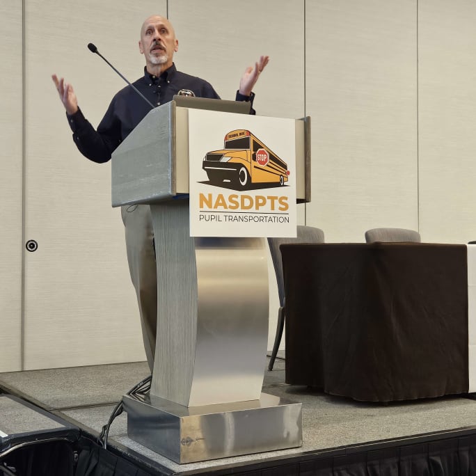 michael graham stands at a podium with a NASDPTS logo on the front