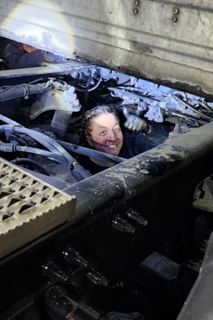 Technician's head peeking up through a truck chassis