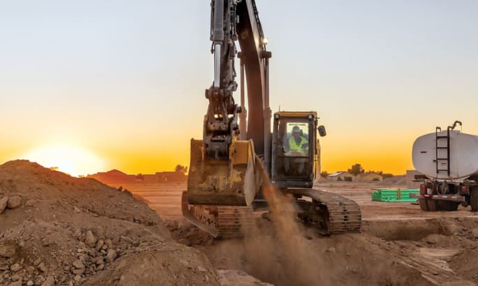 John Deere P-Tier midsize excavator digging soil at a construction site during earthmoving operations.