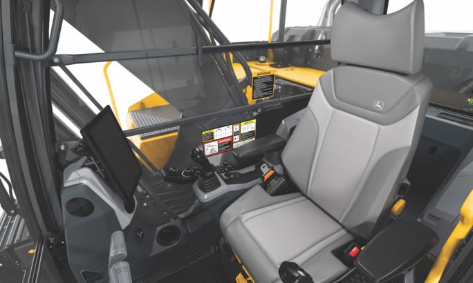 Interior view of a John Deere P-Tier excavator cab showing the operator seat, control joysticks, touchscreen display, and safety features.
