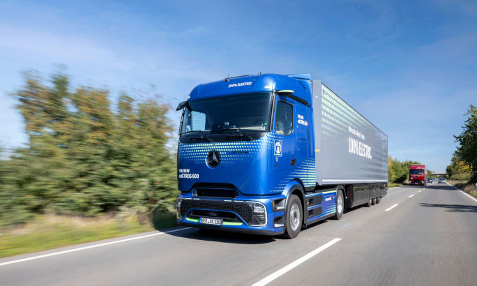 Blue Mercedes-Benz eActros 600 electric semi-truck driving on a highway.